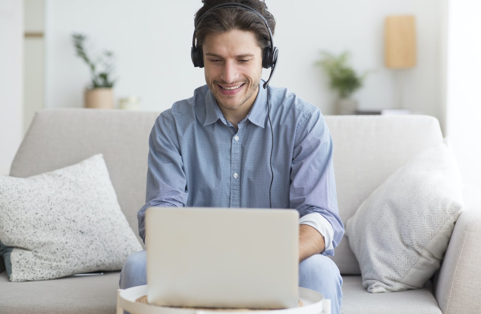 Man In Earphones Using Laptop Listening To Podcast At Home